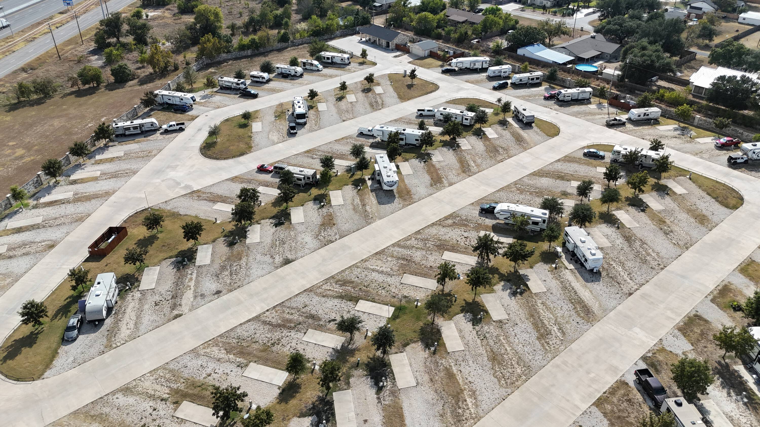 Cream pad rows and young trees from the air — utility pedestals visible, lanes open, occupancy honest. Layout and bones without a broker overlay.